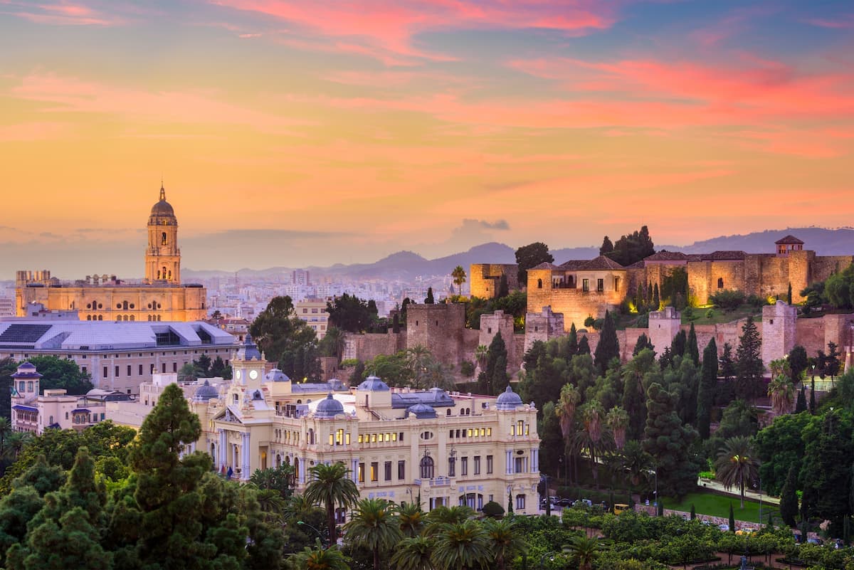 Cityscape with cathedral tower and Alcazaba fortress at sunset in Spain