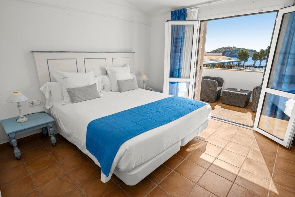 Hotel room with double bed and balcony overlooking the sea.