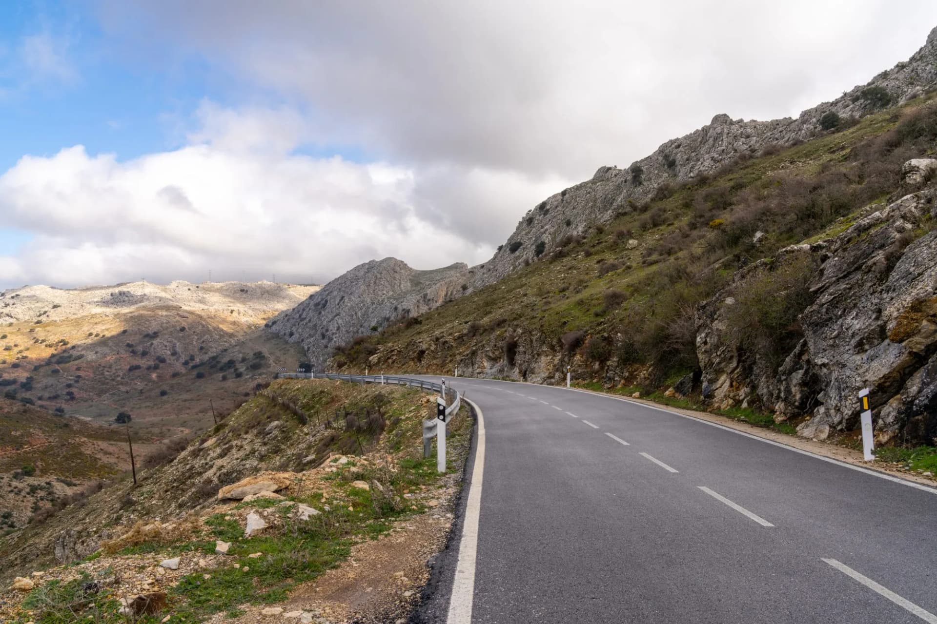 Winding mountain road in Sierra de las Nieves near Malaga, Southern Spain, under cloudy sky.