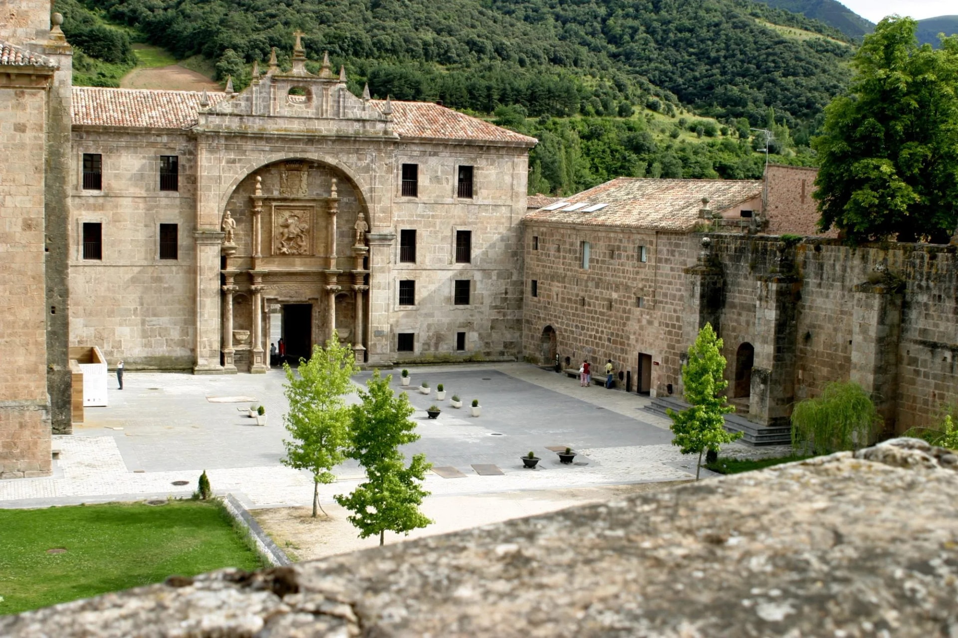 Monastery courtyard in San Millán de la Cogolla, La Rioja, Spain, with forested hills.