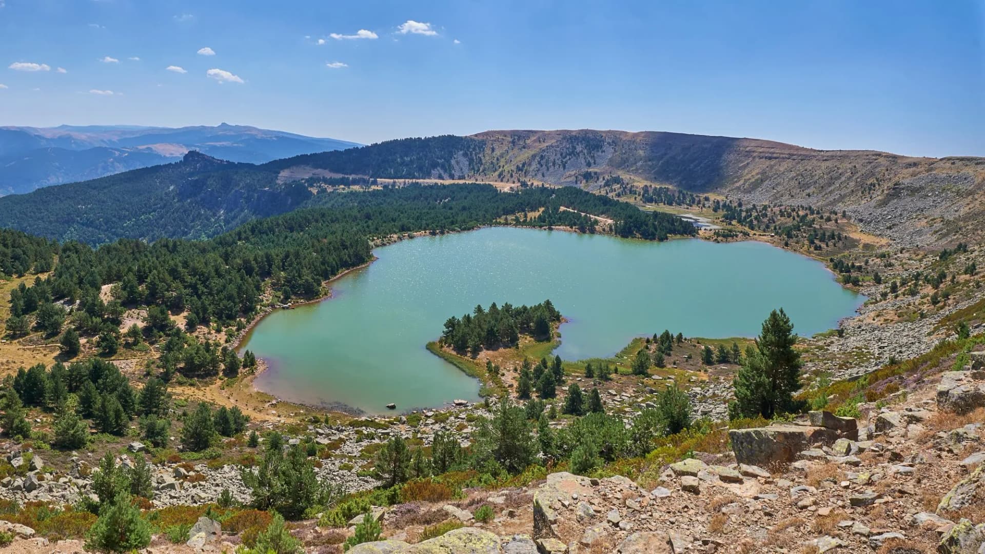 Glacial lake surrounded by pine forests and rocky peaks near the Sierra de la Demanda, Burgos.