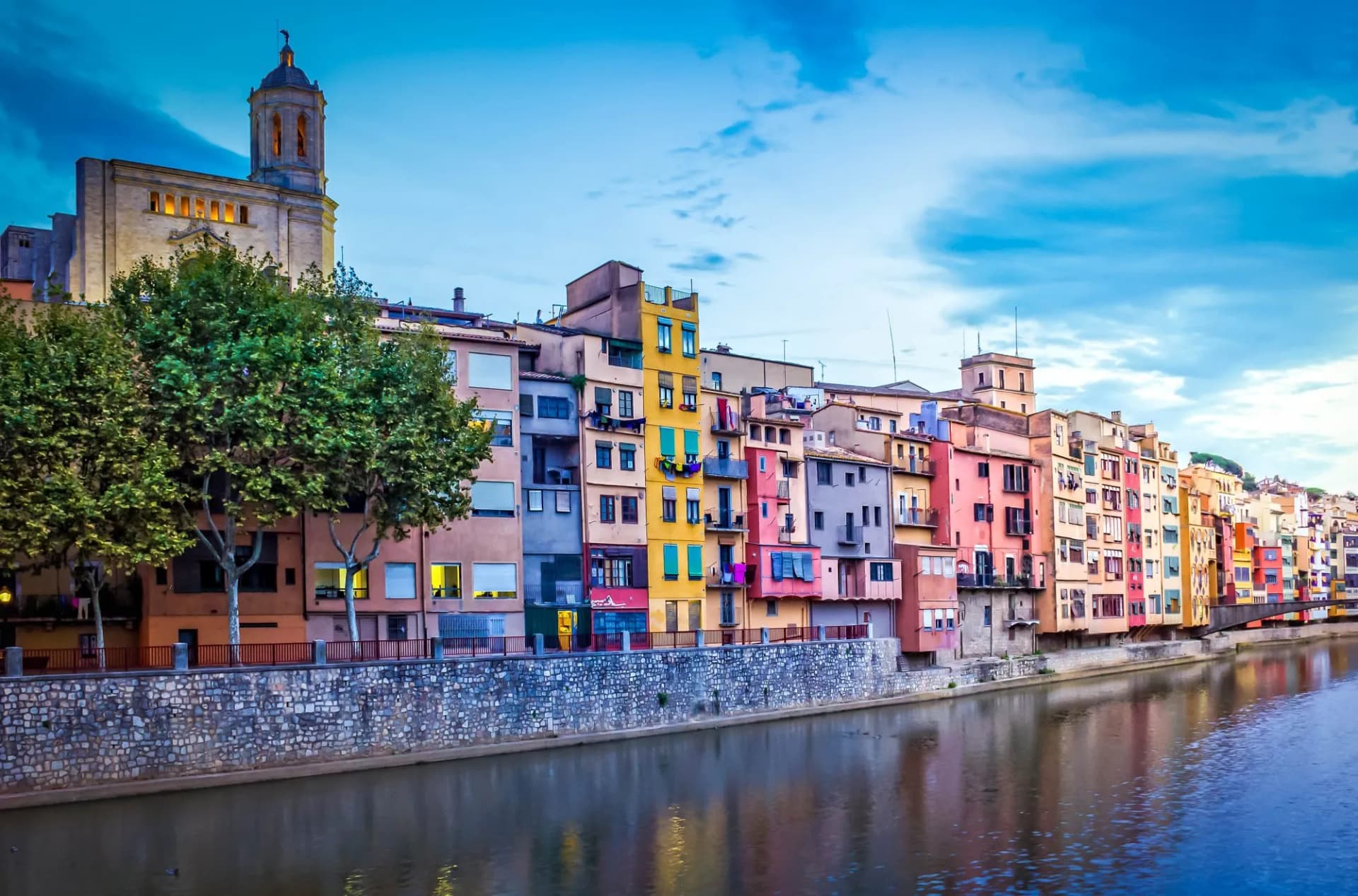 Old town of Girona with colorful houses along the Onyar River at dusk, Spain.