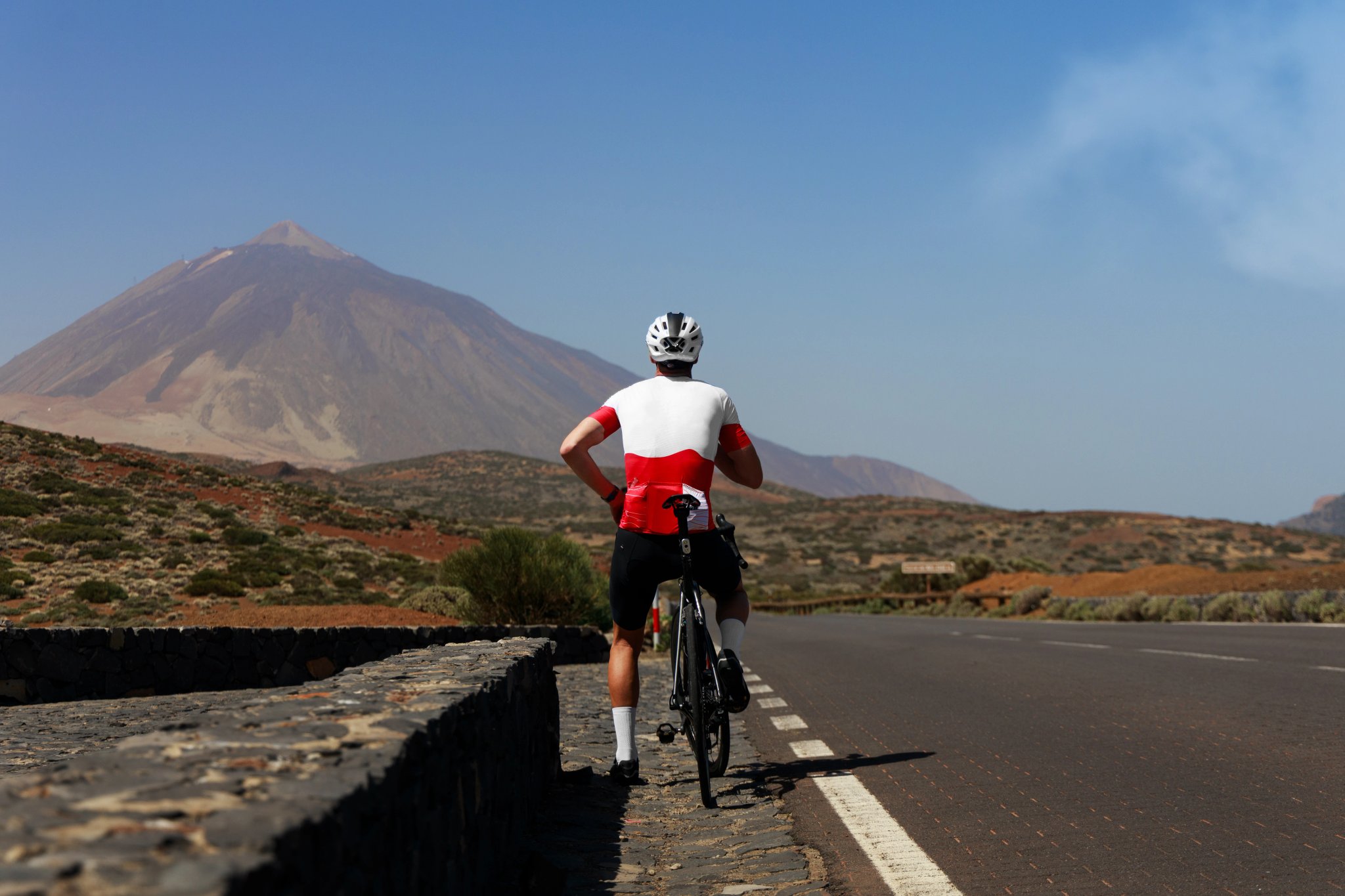 Cyclist on the road with a volcano in the background. Cyclist in Tenerife. Cyclist on the side road enjoying the majestic view