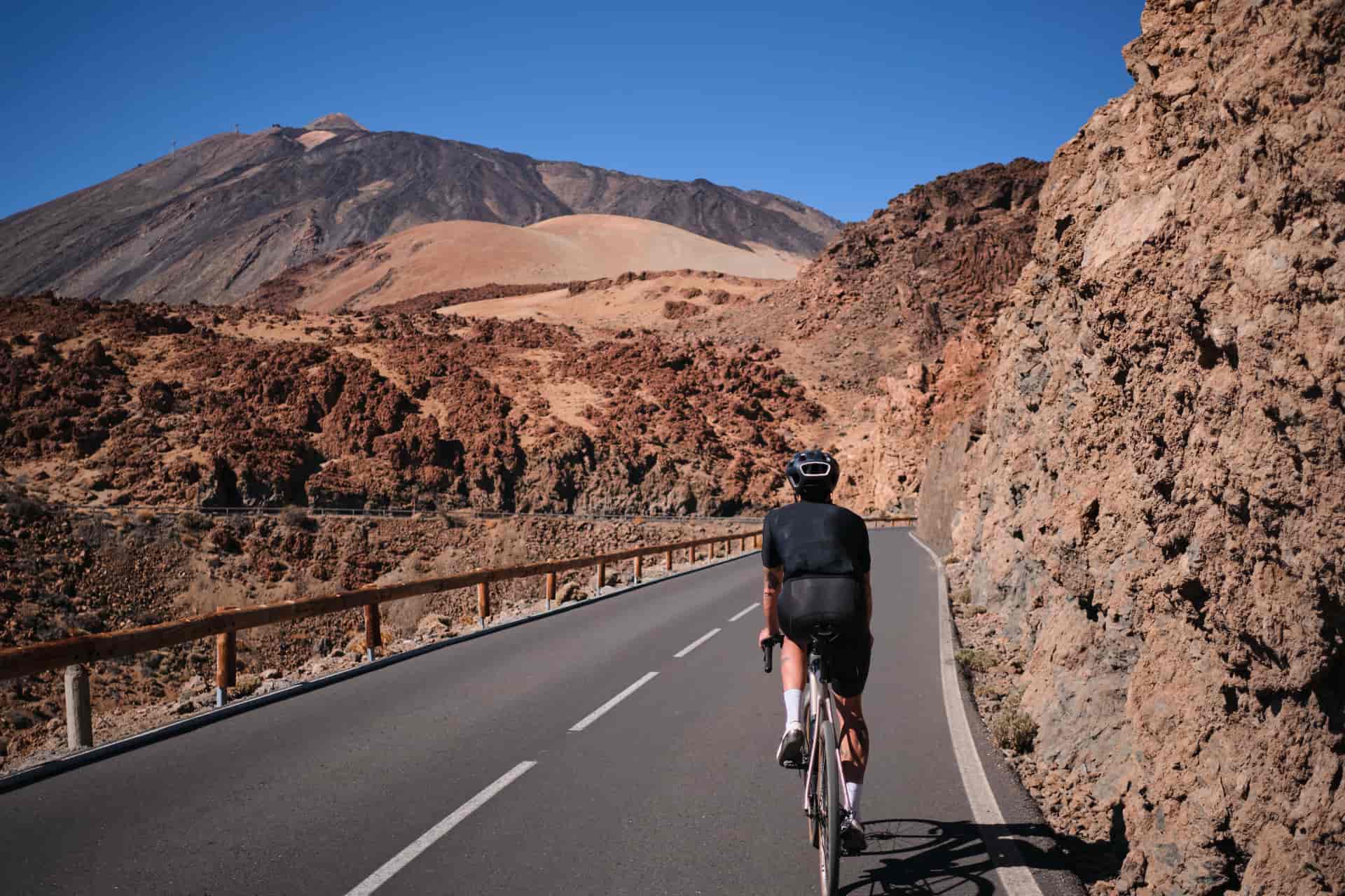 Man cyclist pedaling on road with view on mountain Teide volcano,Tenerife,Canary Islands,Spain. Sportsman training hard on bicycle outdoors.Sport motivation.Cycling training outdoors.Hipster cyclist.