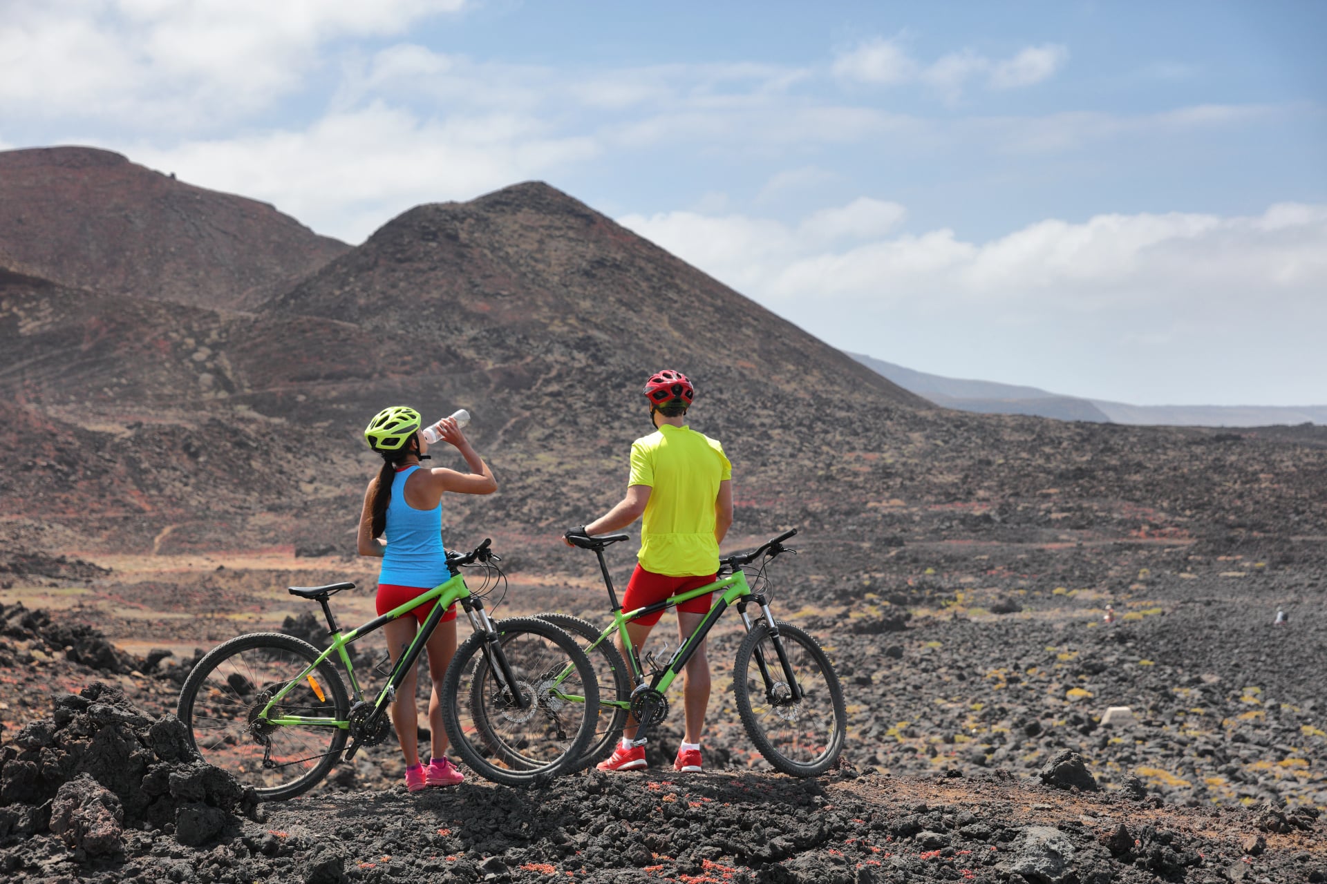 Cykelaventyr med mountain MTB cykler, cyklist cykler på ekstrem lava vulkansk landskab. To cyklister i guidet gruppetur på sommerferie i Lanzarote, De Kanariske Øer, Spanien.