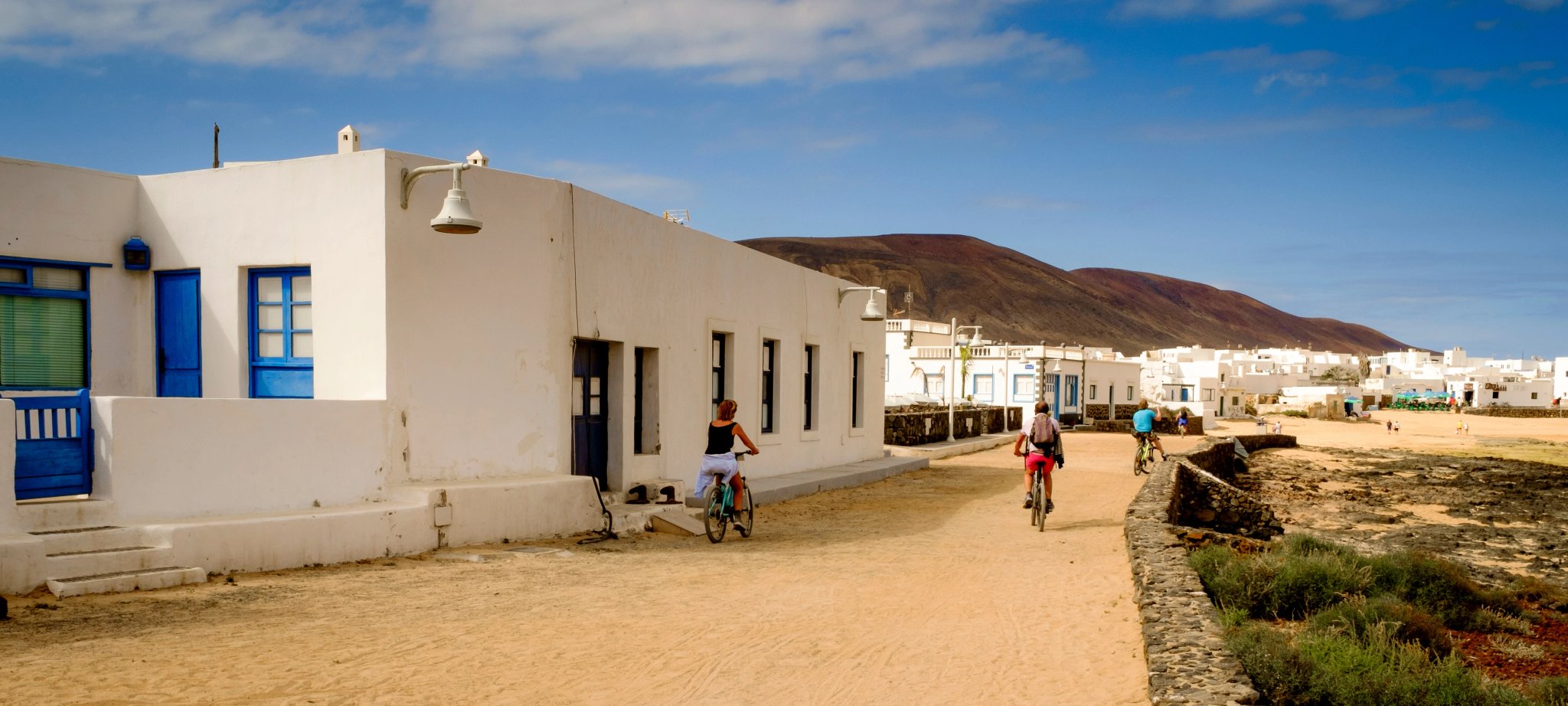 tourist cycling in caleta de sebo street, la graciosa, canary islands