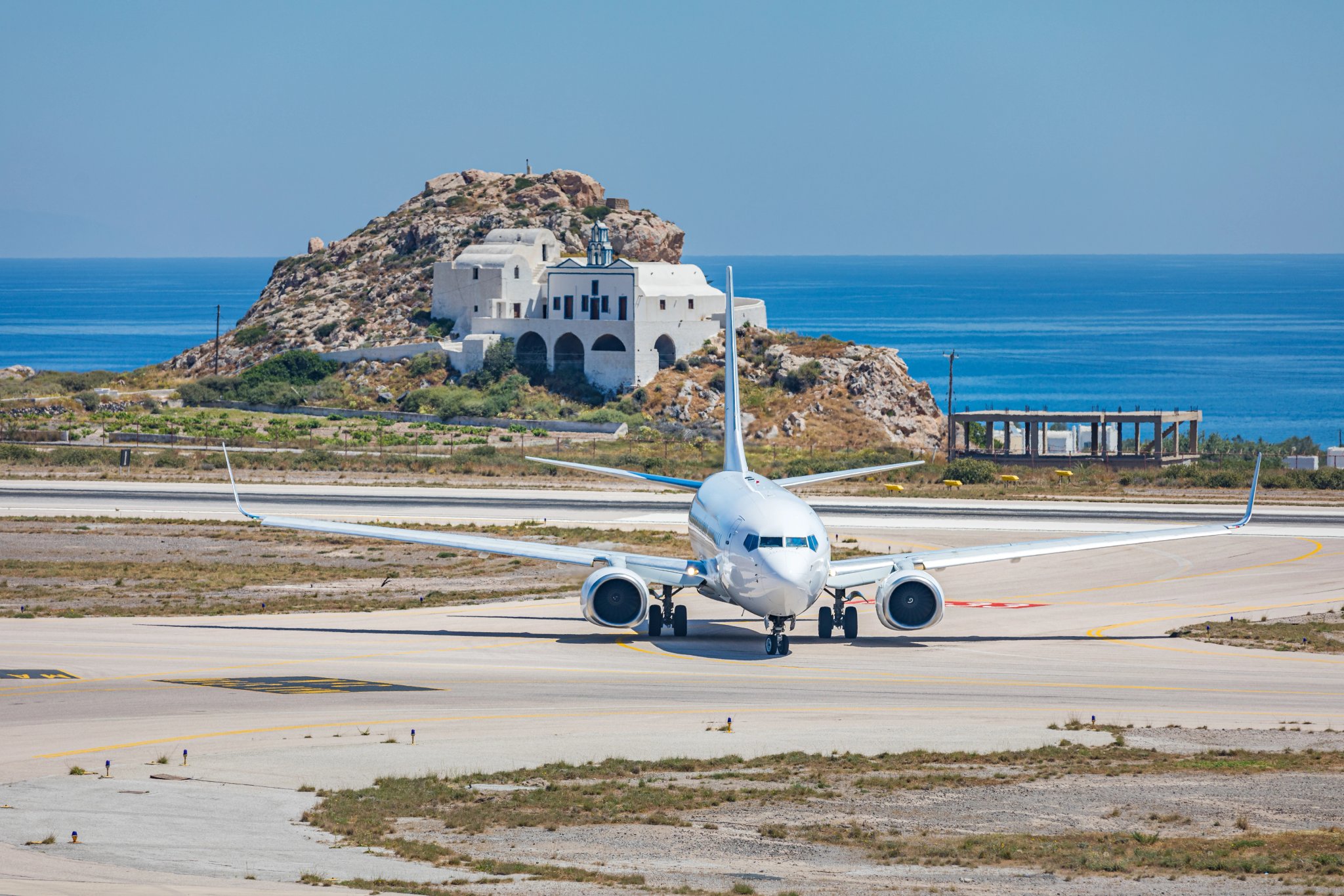 White airplane in airport runaway with sea on the background