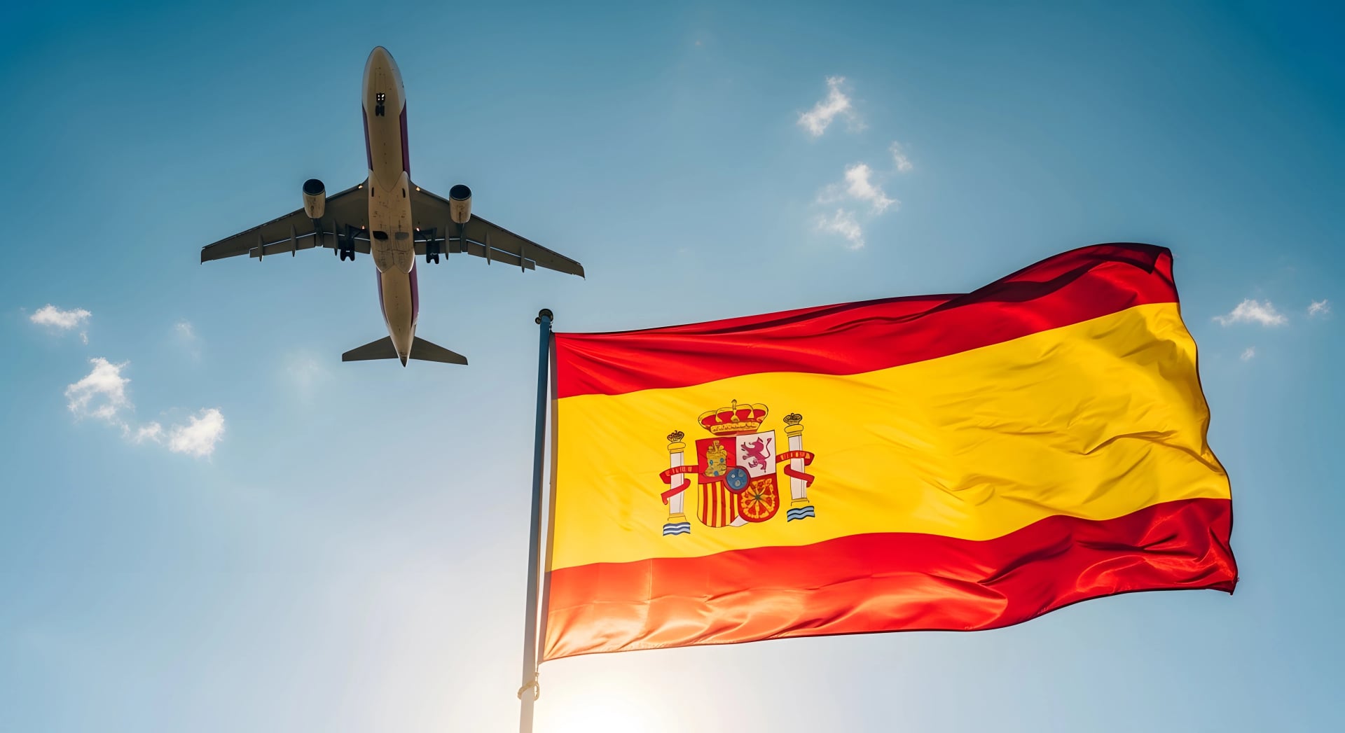 Spanish flag waving in the sky with an airplane flying overhead.