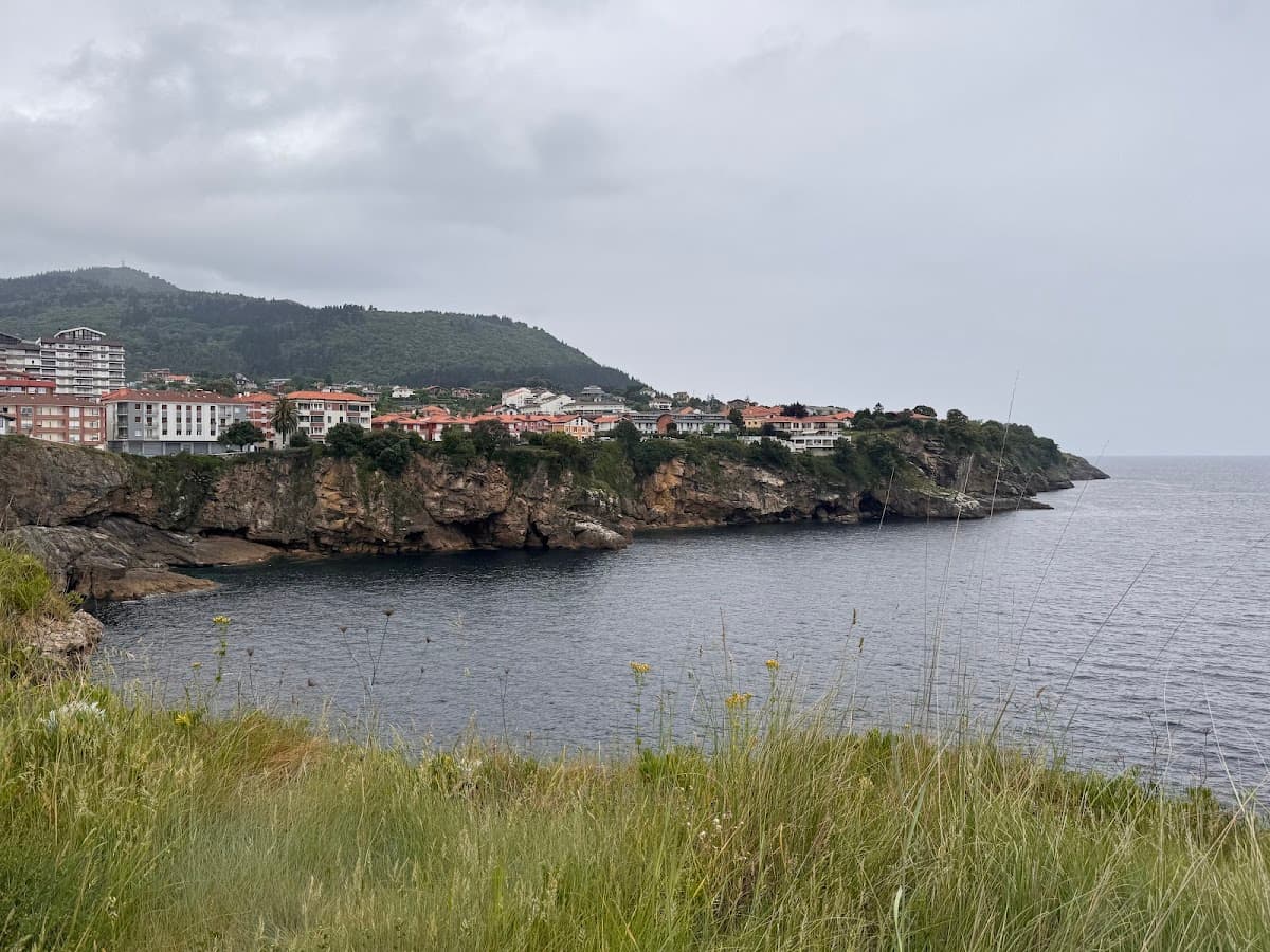 Coastal town with buildings on rocky cliffs overlooking the sea under a cloudy sky