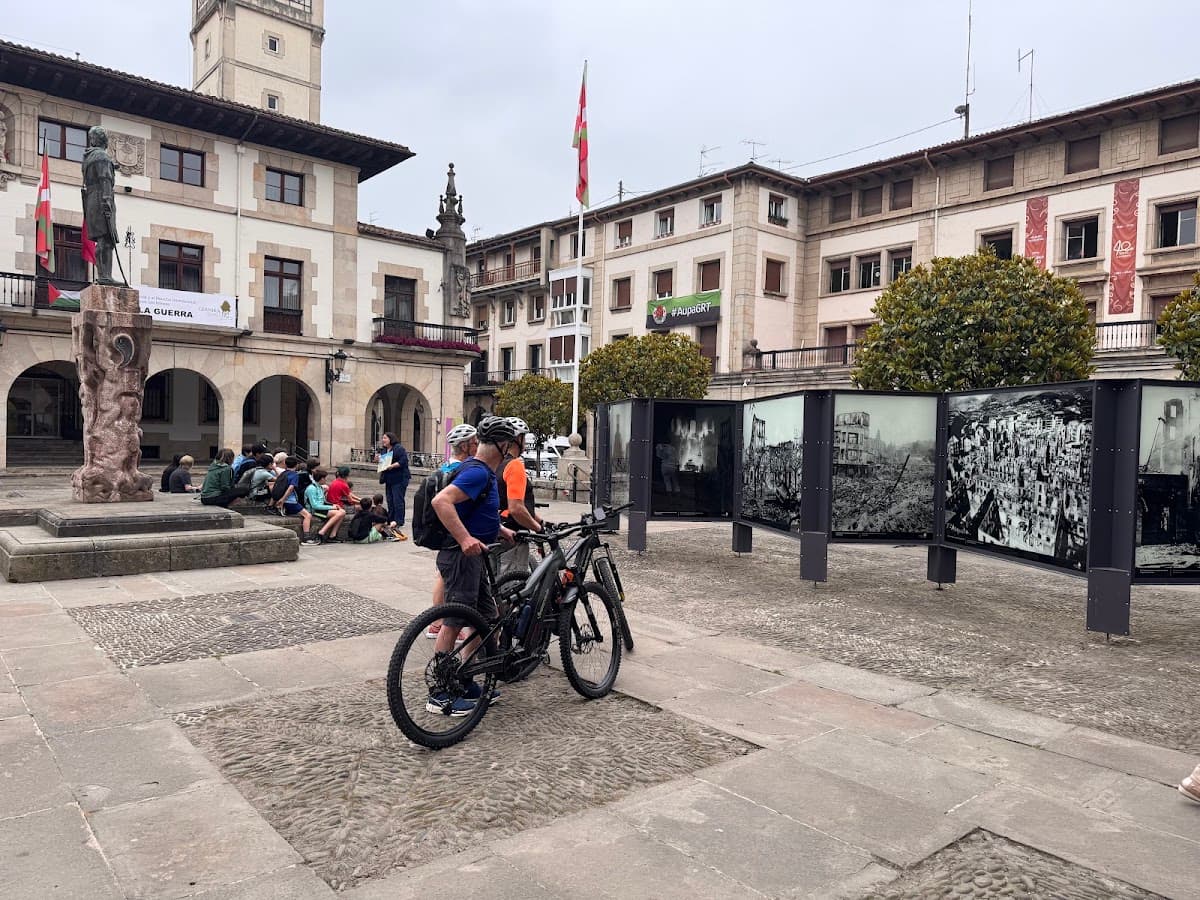 Cyclists with mountain bikes in historic European town square with outdoor photo exhibition