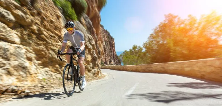 Uomo Adulto su una bici da corsa che sale la collina al mare mediterraneo paesaggio strada costiera su mallorca isola balearica