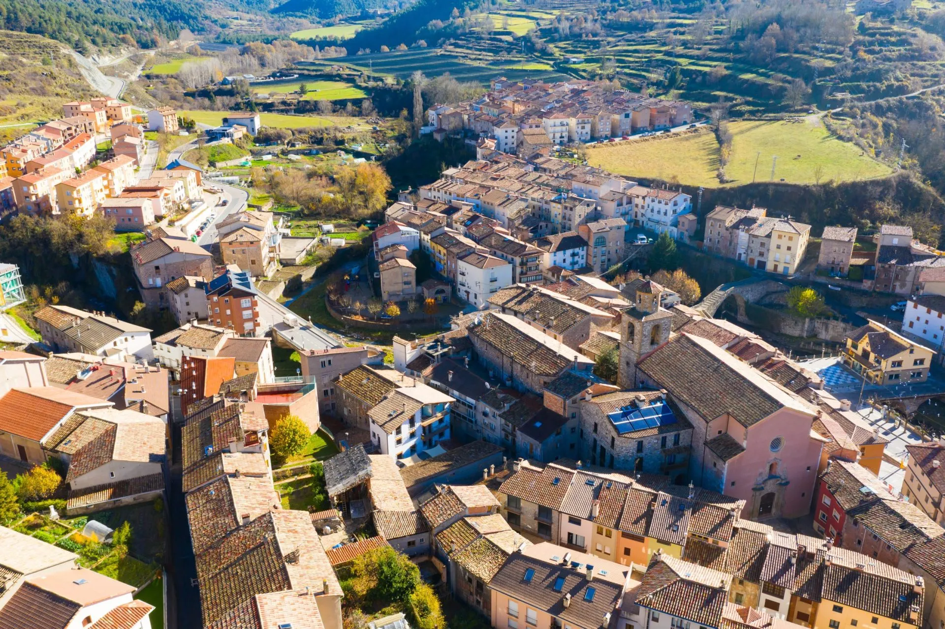 Scenic aerial view of small Spanish town of La Pobla de Lillet at foot of Pyrenees mountains on sunny fall day, Catalonia